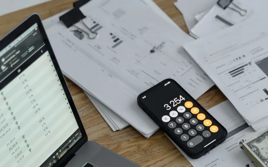 Un ordinateur portable, une calculatrice et des graphiques sur un bureau